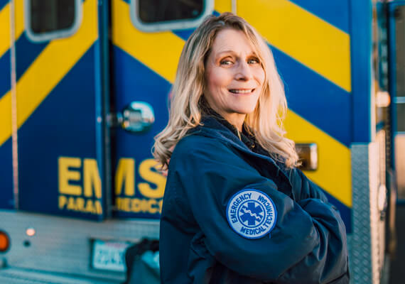 Emergency medical services women stands next to ambulance